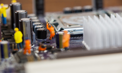 Conceptual image of miniature workers working on chip of motherboard